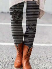 Striped flared trousers with a black cat print, paired with brown boots.