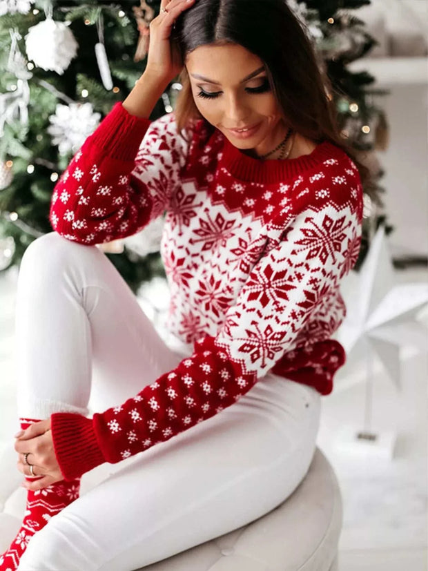 Woman wearing red and white snowflake pattern long sleeve sweater sitting by Christmas tree