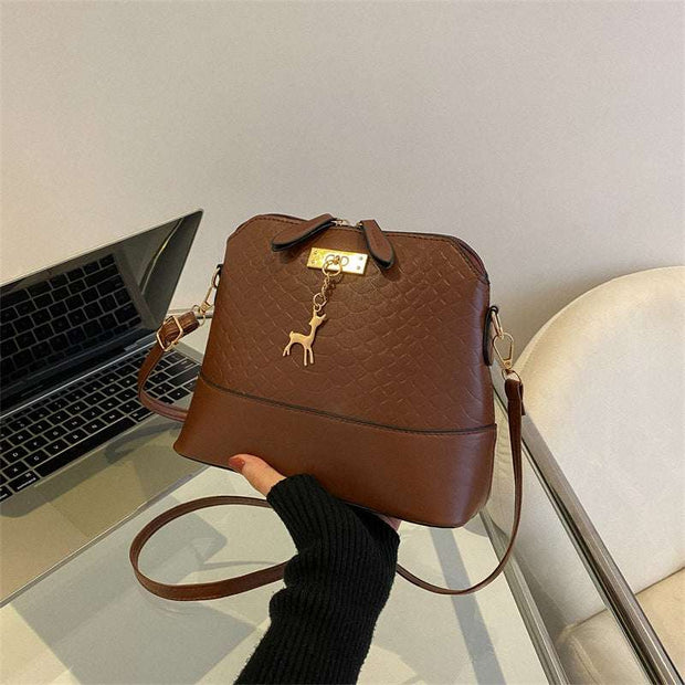 Womens Mini Portable Handbag in brown PU leather with telescopic handle, showcasing compact and chic design on a table.