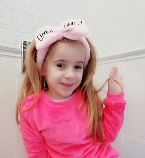 Girl wearing Coral Velvet Butterfly Hair Band with playful butterfly design.