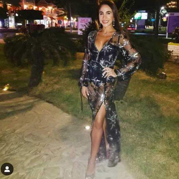 Elegant woman wearing a stylish black lace dress with intricate sequins and high slit, suited for formal occasions.