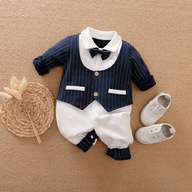 Baby Gentleman Jumpsuit with bowtie and pocket details, paired with baby shoes on a woven mat.