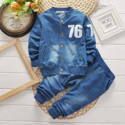 Boys denim suit with jacket and pants, featuring number 76, styled on white wooden background.
