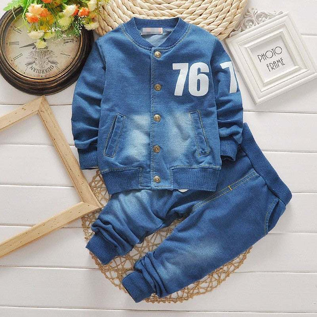 Boys denim suit with jacket and pants, featuring number 76, styled on white wooden background.