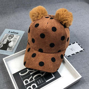 Ball Peaked Hat with dots, double ball design, in ginger corduroy, on a gray surface.
