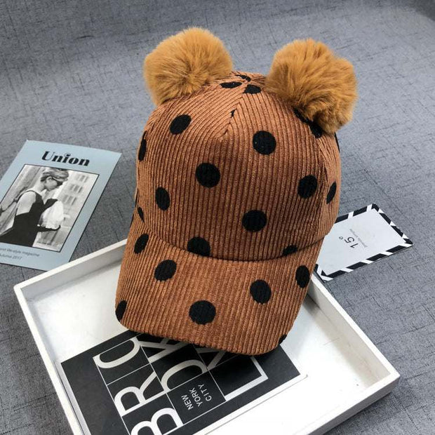 Ball Peaked Hat with dots, double ball design, in ginger corduroy, on a gray surface.