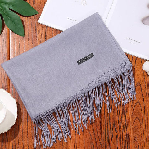 Designer scarf shawl on table with intricate fringe detailing.
