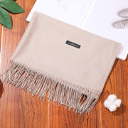 Luxury designer scarf shawl in beige cashmere on wooden surface.