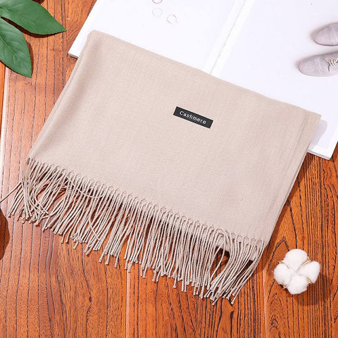 Luxury designer scarf shawl in beige cashmere on wooden surface.