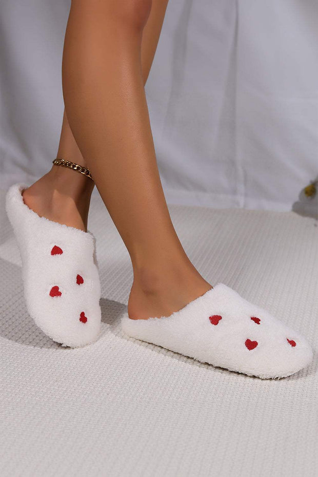 Pink heart embroidered plush slippers on feet, cozy and stylish loungewear.