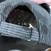 Close-up of the adjustable strap on a dark gray corduroy Ball Peaked Hat with double ball design.