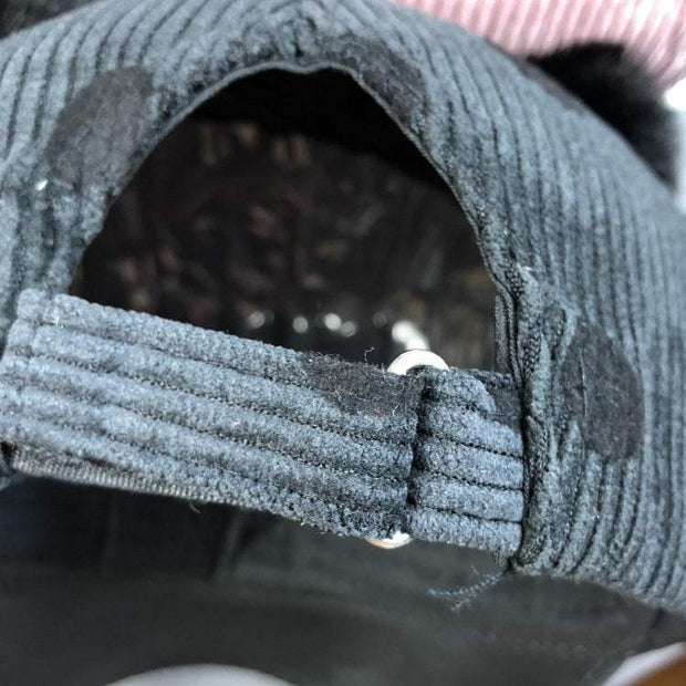 Close-up of the adjustable strap on a dark gray corduroy Ball Peaked Hat with double ball design.