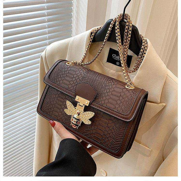 Chain shoulder bag with elegant design and gold accents hanging on a beige jacket.