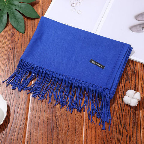 Blue designer scarf shawl with fringes, elegantly displayed on a wooden surface.