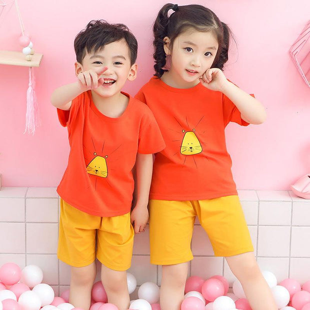 Kids wearing matching orange and yellow Youth Cotton Short-Sleeve Suits with cartoon design.