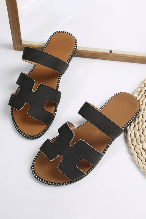 Black leather H band slides with cushioned footbed on white background.