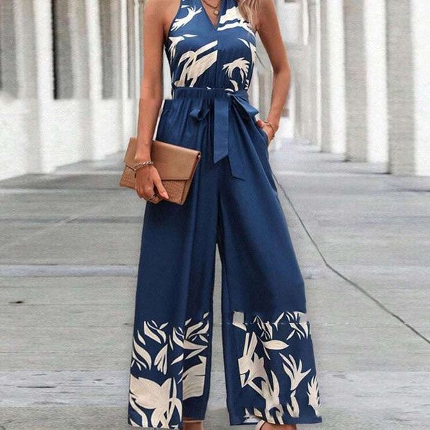 Women's backless halter jumpsuit in blue with a tropical print, featuring a fitted bodice and wide-leg trousers.