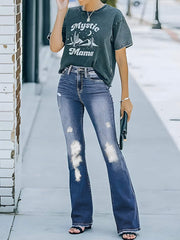 Distressed bootcut jeans with stylish rips, medium wash, paired with a graphic tee and heels.