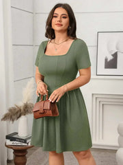 Plus size square-neck short-sleeve mini dress in green, styled with a brown handbag.