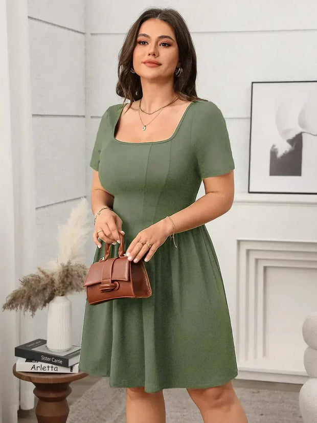 Plus size square-neck short-sleeve mini dress in green, styled with a brown handbag.