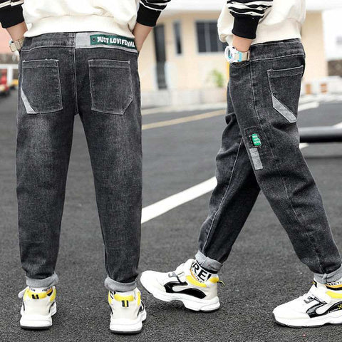 Boys wearing black washed denim jeans with green waist patch, showcasing casual style and reinforced durability.