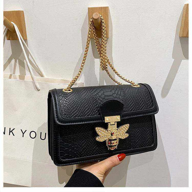 Black chain shoulder bag with gold bee embellishment and chain strap.
