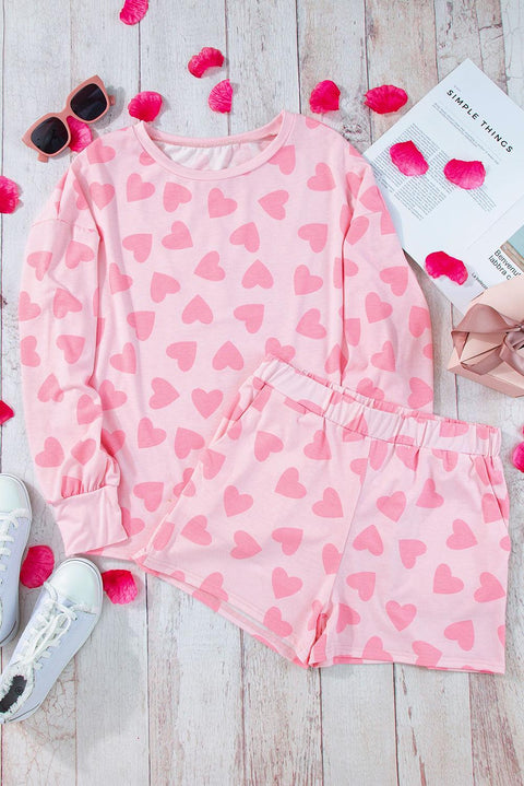 Pink heart print loungewear set featuring a cozy top and matching shorts on a wooden background.