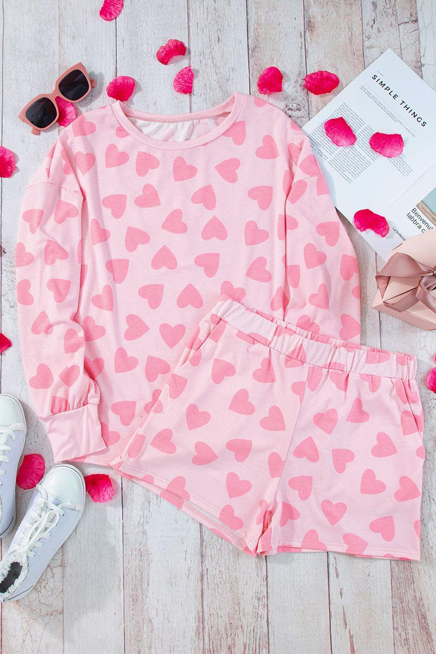 Pink heart print loungewear set featuring a cozy top and matching shorts on a wooden background.