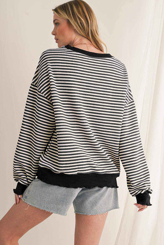 Woman wearing black and white striped drop shoulder long sleeve top with black cuffs and hem paired with denim shorts viewed from the back