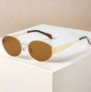 Metal oval vintage sunglasses with gold frame and brown lenses on white background.