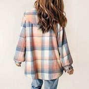 Woman wearing a plaid hooded fleece-lined jacket in pastel shades of pink, blue, and white, styled with blue jeans, back view.