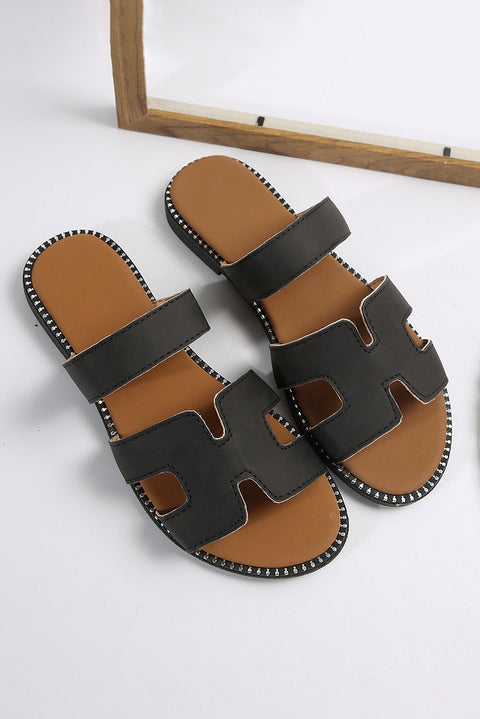 Black leather slides with H band design and cushioned footbed.