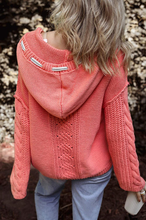 Cable-knit hooded sweater in coral with drawstring, featuring a classic design for warmth and style.