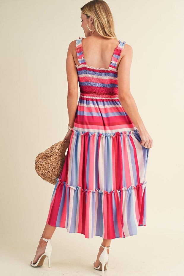 Woman wearing a Red Stripe Smocked Midi Dress with tiered skirt and ruffled straps, holding a round straw bag.
