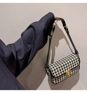 Houndstooth Baguette Bag with gold clasp and black shoulder strap.