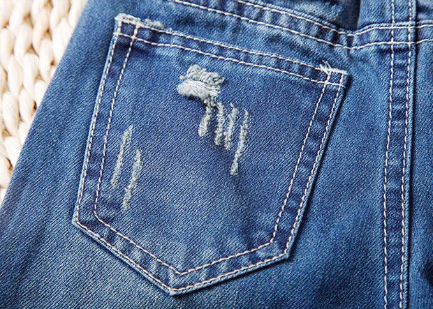 Close-up of trendy distressed back pocket on European style boys ripped jeans.