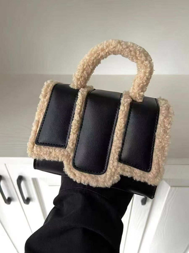 Black lambs wool crossbody bag with PU trim and handle.