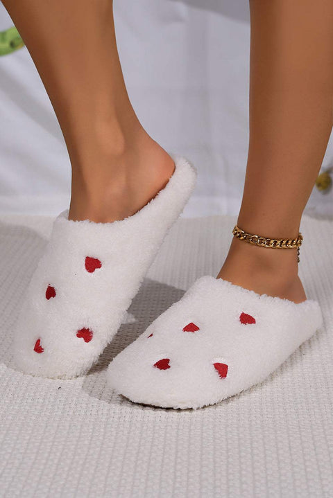 Pink heart embroidered plush slippers on feet, cozy and stylish.