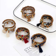 Wooden stretch bracelets with tassels and beads in various colors on a white tray.