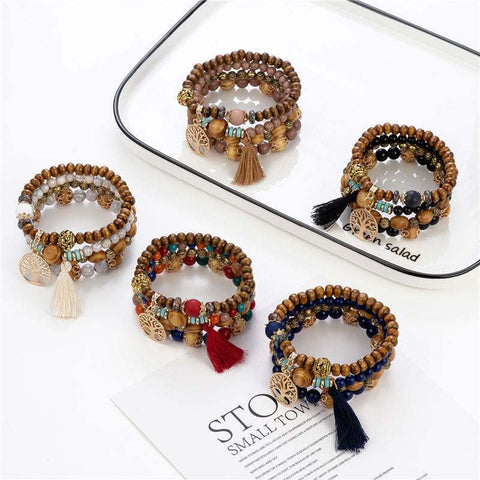 Wooden stretch bracelets with tassels and beads in various colors on a white tray.