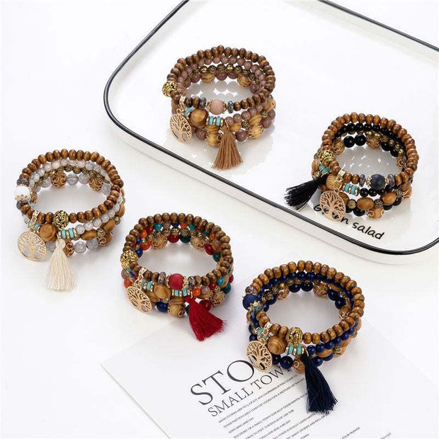 Wooden stretch bracelets with tassels and beads in various colors on a white tray.