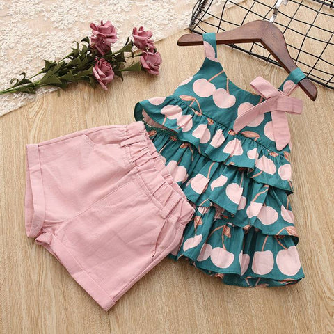 Cake Skirt Camisole Set with pink shorts and playful design on wooden background.