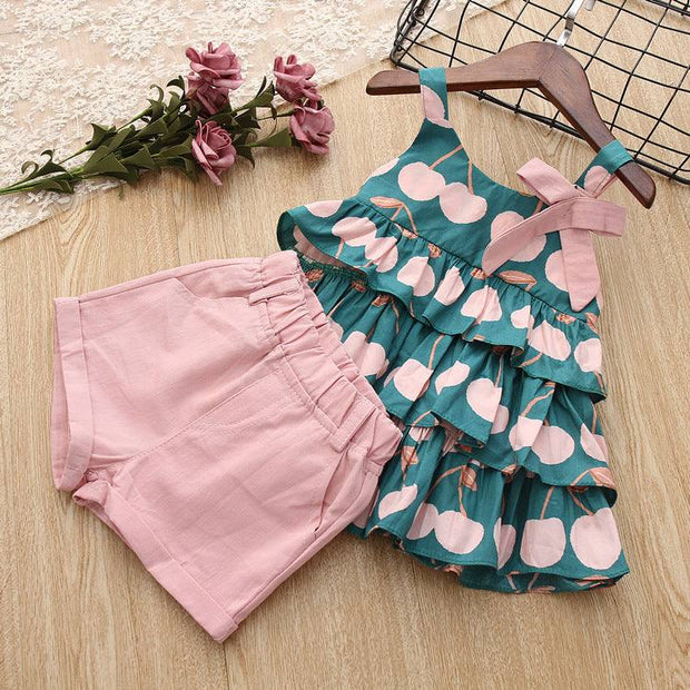 Cake Skirt Camisole Set with pink shorts and playful design on wooden background.