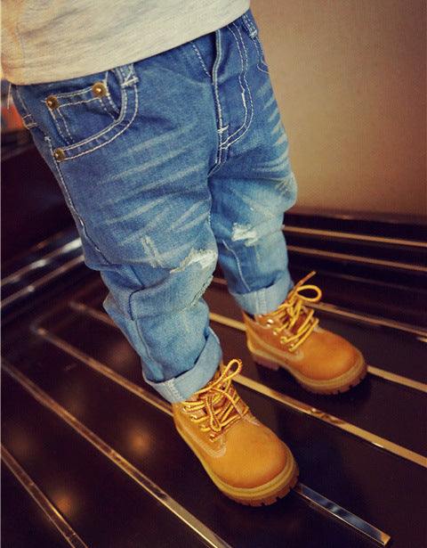 European style boys ripped jeans with distressed details and rolled-up cuffs.