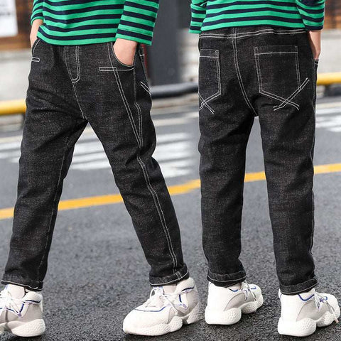 Boys wearing black denim jeans with white sneakers and green striped shirts.
