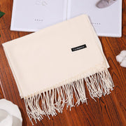Designer scarf shawl in soft cashmere with fringe detailing, displayed on wooden table.