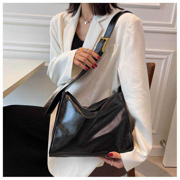 Retro Crossbody Commuter Tote in black PU material with an adjustable strap, held by a woman wearing a white jacket.
