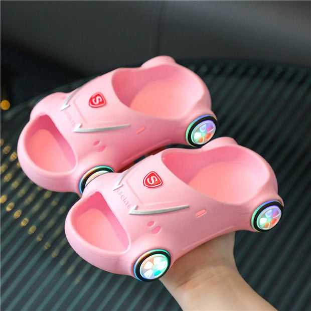 Kids glowing slippers in pink car design with LED lights and non-slip soles for comfort and safety.