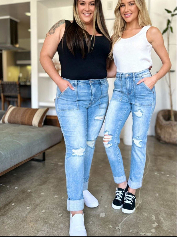 Two women wearing Judy Blue distressed jeans standing in a living room.