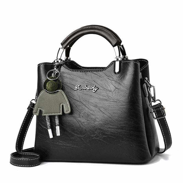 Small Retro Handbag in black PU leather with top handle and shoulder strap, featuring decorative charm.